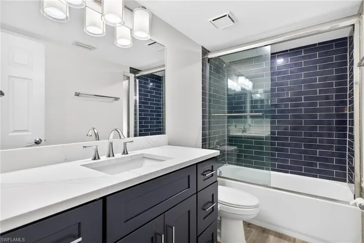 Full bathroom featuring vanity, combined bath / shower with glass door, and light wood-style floors