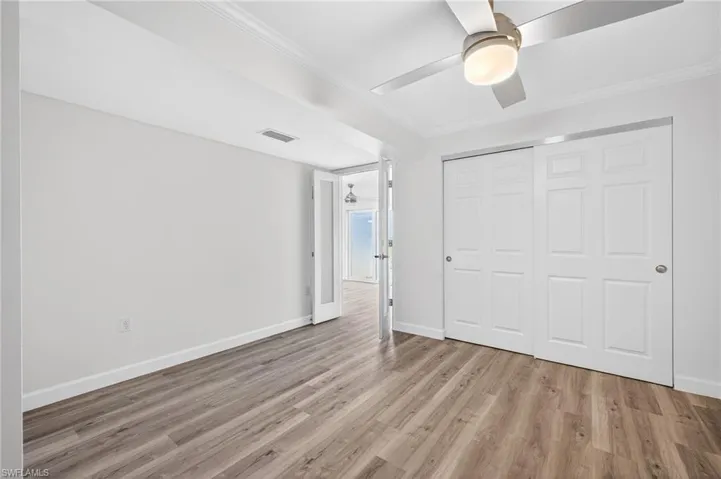 Unfurnished bedroom featuring ornamental molding, light wood-style floors, a closet, and ceiling fan