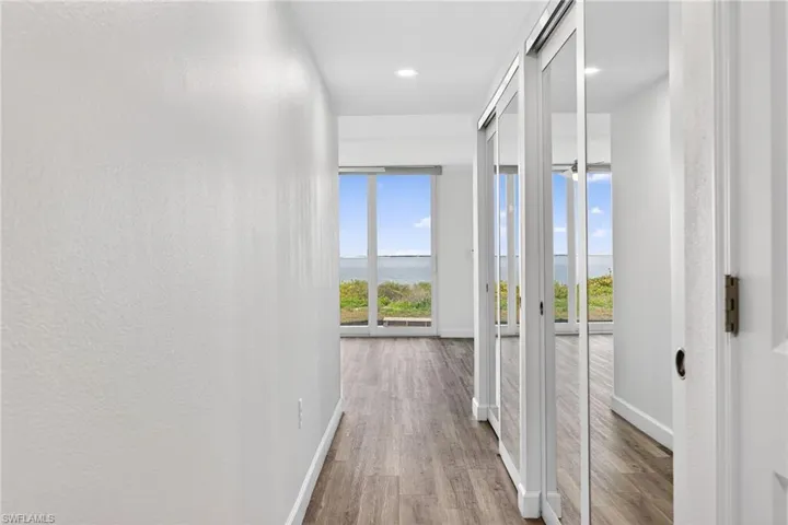 Hallway featuring a water view, light wood-style flooring, plenty of natural light, and recessed lighting