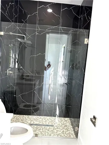 Bathroom with a marble finish shower, tile patterned flooring, and vanity