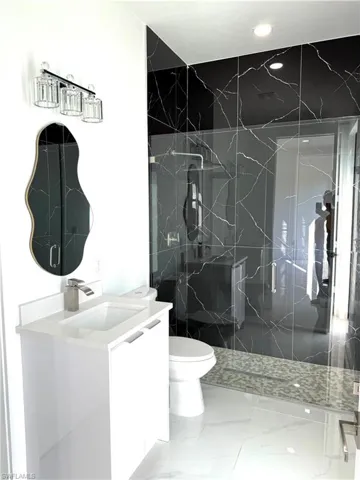 Full bathroom with vanity, a marble finish shower, and light marble finish flooring