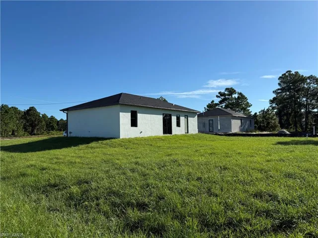 Back of house with stucco siding and a yard