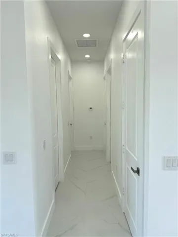 Hallway featuring light marble finish floors and recessed lighting