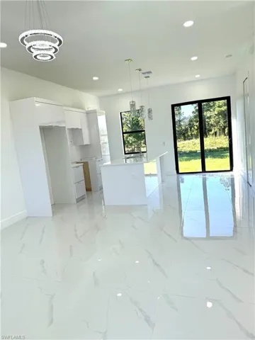 Kitchen with white cabinetry, light marble finish floors, modern cabinets, decorative light fixtures, and recessed lighting