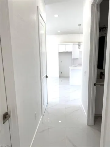 Hallway featuring light marble finish flooring and recessed lighting