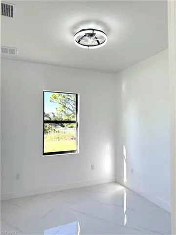 Empty room with baseboards and marble look tiles