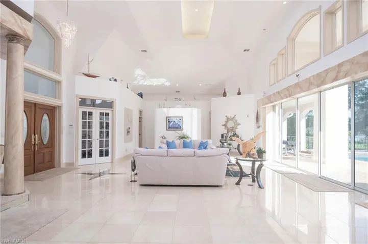 Living area with lots of windows, glass sliders, plant shelves and decorative columns.