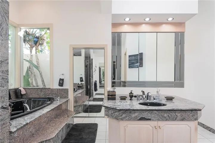 Guest bath features dual vanities & sinks, large walk in shower, garden spa tub & water closet.