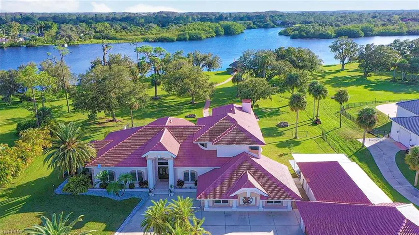 Up close picture of the main home with winding paver pathway to firepit, waterfront tiki hut and boat dock/lifts. This stately home and tile roof was just repainted outside in 2024 and roof was resealed. No known hurricane damage.