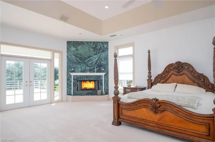 Spacious and private Master Bedroom with Trey ceilings, wood burning granite fireplace, french doors to patio overlooking the pool, ground and river. Also 2 custom walk in closets!