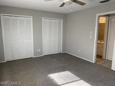 Unfurnished bedroom featuring multiple closets, carpet, ceiling fan, and connected bathroom