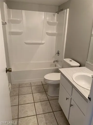 Full bathroom featuring shower / bathtub combination, vanity, toilet, and tile patterned floors