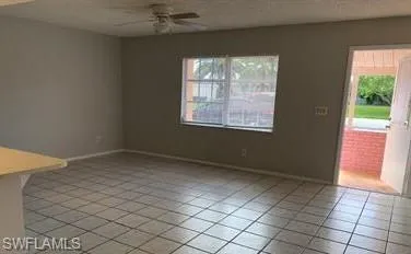 Unfurnished room with a wealth of natural light, light tile patterned floors, and ceiling fan
