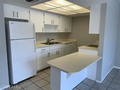 Kitchen featuring sink, white cabinetry, white refrigerator, and light tile patterned floors