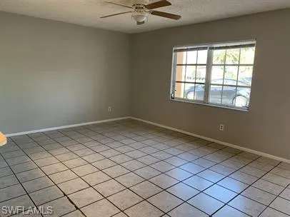 Tiled spare room featuring ceiling fan