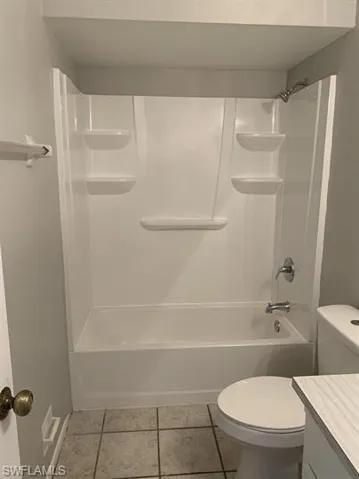 Full bathroom featuring tile patterned floors, toilet, vanity, and shower / tub combination