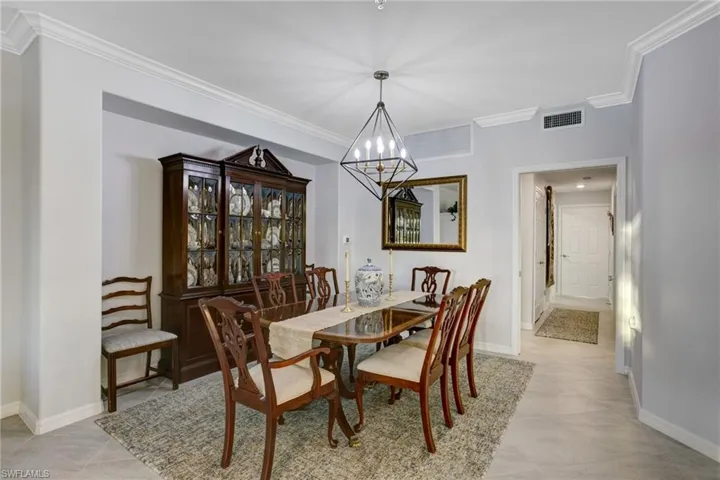Dining area with crown molding, a chandelier, and light tile patterned floors