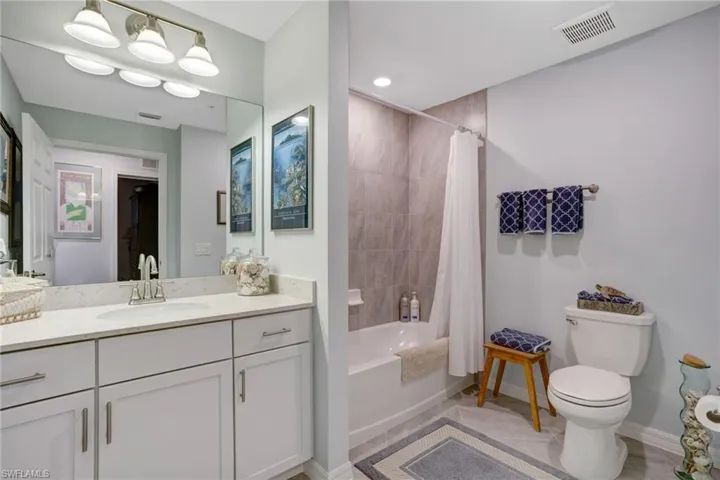 Bathroom with shower / bathtub combination with curtain, vanity, and light tile patterned floors