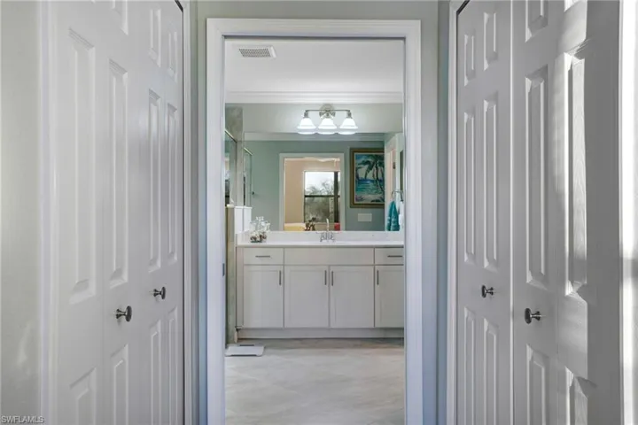 Full bath featuring vanity, a shower with shower door, ornamental molding, and a closet