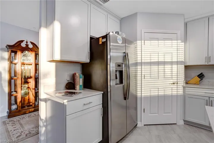 Kitchen featuring stainless steel fridge with ice dispenser, light stone countertops, and white cabinetry