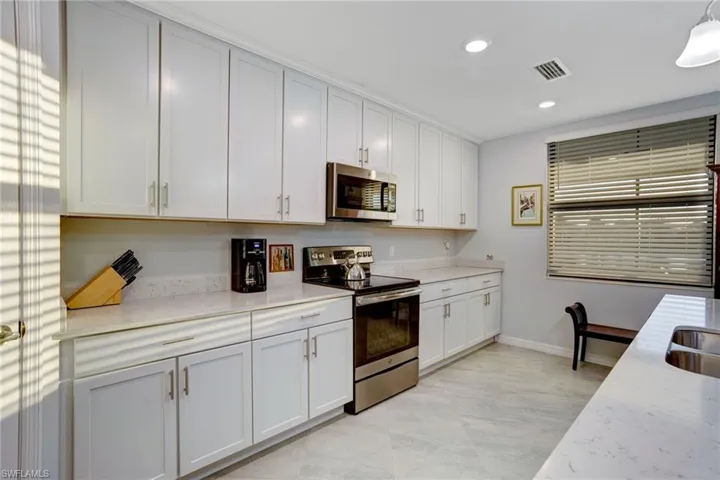 Kitchen with stainless steel appliances, light stone countertops, white cabinetry, and recessed lighting