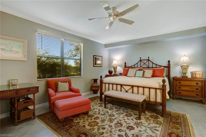 Bedroom with light tile patterned floors, crown molding, and ceiling fan