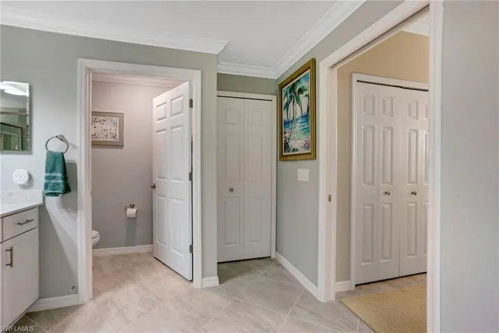 Bathroom featuring a closet, vanity, and ornamental molding