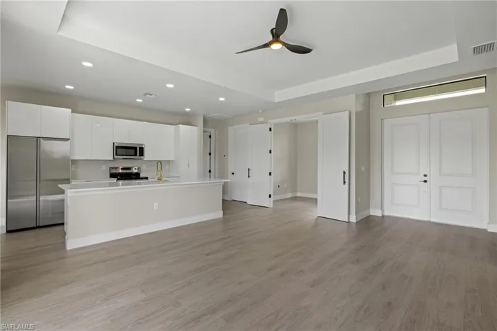 Kitchen with white cabinets, appliances with stainless steel finishes, and a raised ceiling