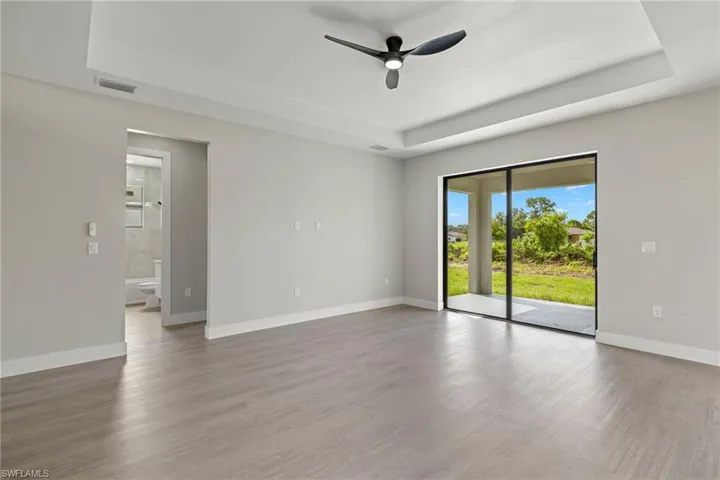 Unfurnished room featuring a tray ceiling, wood-type flooring, and ceiling fan
