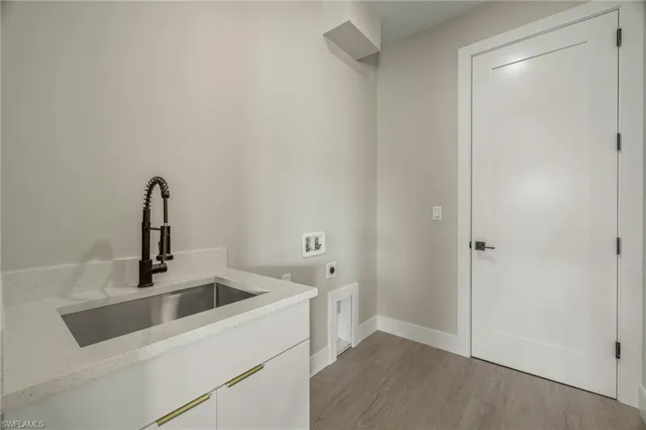Washroom with cabinets, sink, electric dryer hookup, light wood-type flooring, and washer hookup