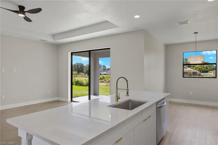 Kitchen featuring light stone countertops, light hardwood / wood-style floors, sink, white cabinetry, and ceiling fan