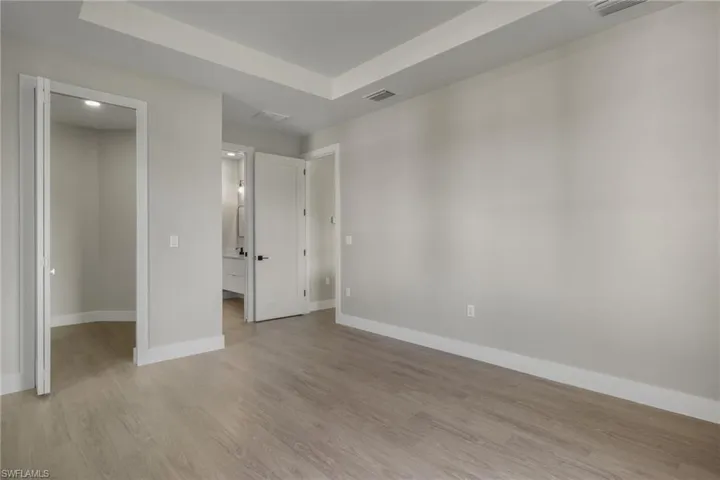 Unfurnished bedroom with a walk in closet and light hardwood / wood-style floors