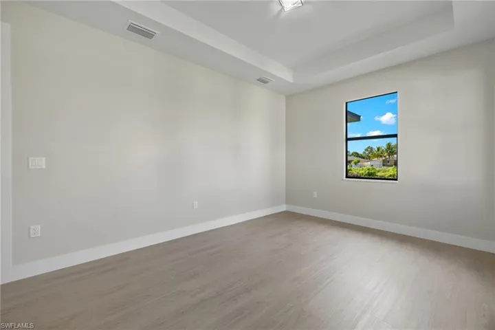 Unfurnished room featuring a tray ceiling and wood-type flooring