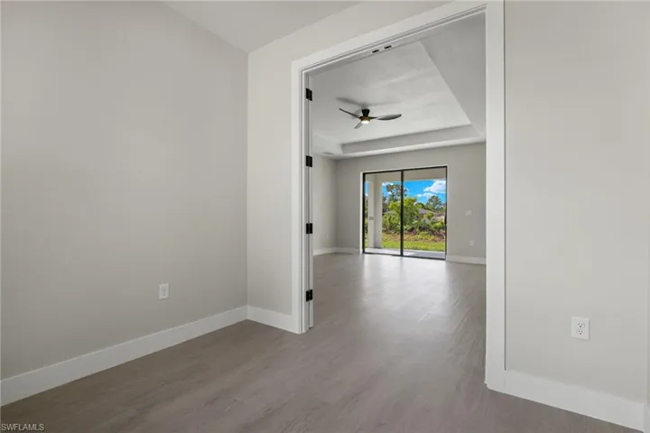Spare room featuring light wood-type flooring, a tray ceiling, and ceiling fan
