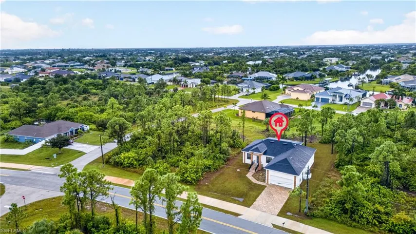 Single-family residence featuring a multi-gabled roof, paved driveway, two-car garage, and established perimeter vegetation