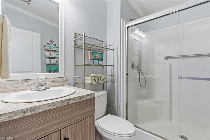 Full bath with crown molding, vanity, a textured wall, and a shower stall