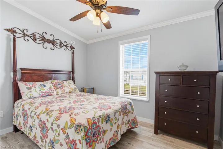 Bedroom featuring crown molding, light wood finished floors, and ceiling fan