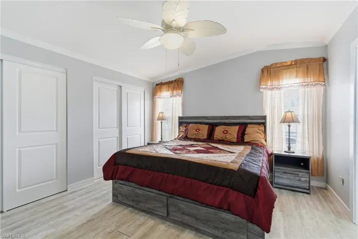 Bedroom featuring crown molding, multiple closets, a ceiling fan, and light wood-style floors