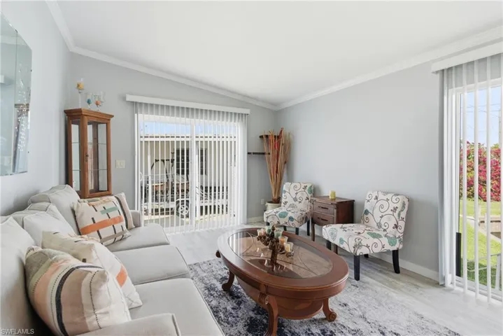 Living area with crown molding, vaulted ceiling, and wood finished floors