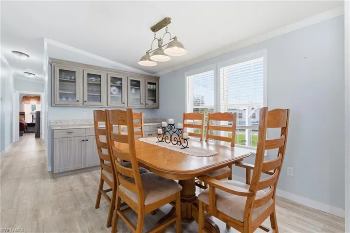Dining space with light wood-style flooring and ornamental molding