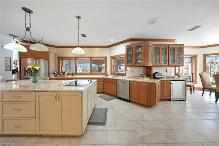 Kitchen with crown molding, stainless steel appliances, a center island, sink, and hanging light fixtures