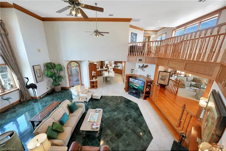 Tiled living room featuring crown molding, a high ceiling, and ceiling fan