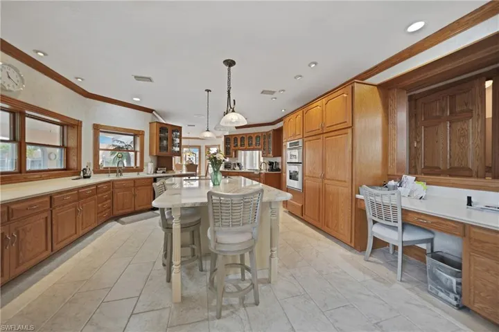 Kitchen featuring a center island, crown molding, sink, double oven, and a kitchen breakfast bar