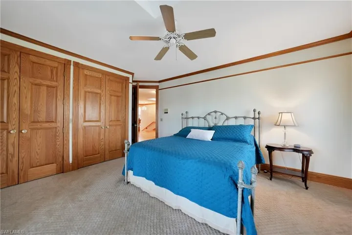 Carpeted bedroom with ornamental molding and ceiling fan
