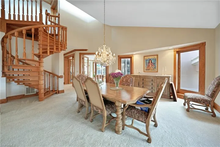 Carpeted dining area featuring high vaulted ceiling and a chandelier