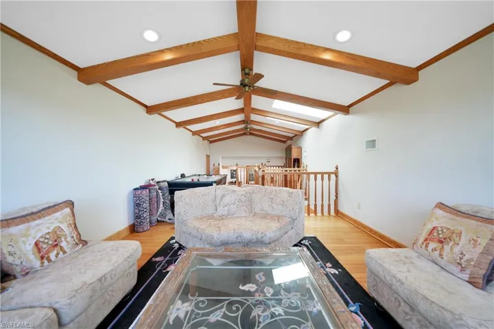 Game Room with light hardwood / wood-style floors, ceiling fan, and vaulted ceiling with beams