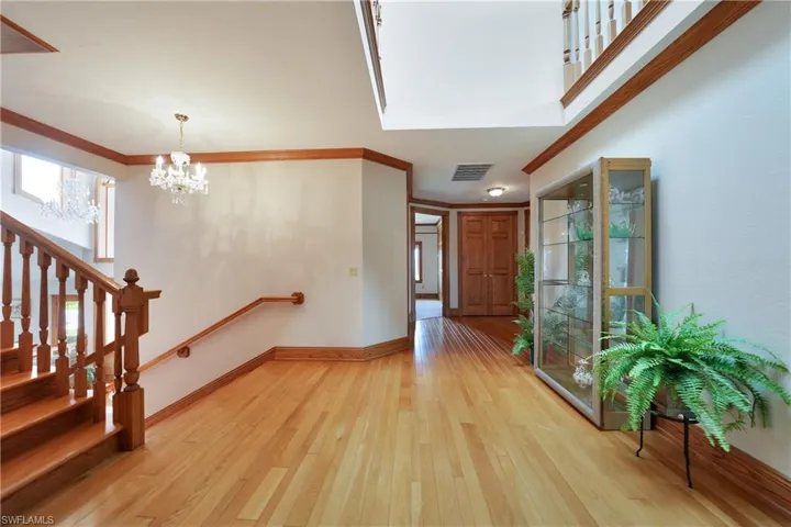 Entryway featuring light wood-type flooring, an inviting chandelier, and crown molding