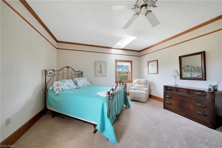 Carpeted bedroom featuring crown molding, a skylight, and ceiling fan
