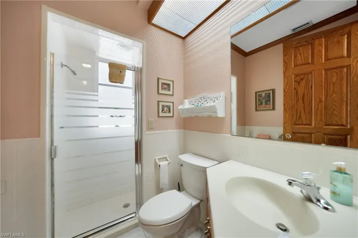 Bathroom with vanity, an enclosed shower, tile walls, toilet, and ornamental molding
