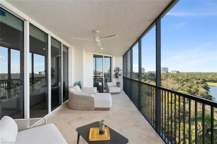 Sunroom with ceiling fan, expansive windows, a balcony, tile patterned flooring, and a textured ceiling